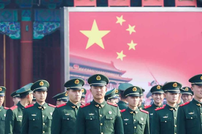 shutterstock_614176682 Group of uniformed soldiers standing before a large red flag