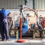 Hiring Cools Despite Lower Jobless Rate Factory worker operates near an industrial robot arm in a workshop