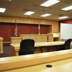 Grieving Mom Torches Capitol Orthodoxy Interior view of an empty courtroom with wooden furniture and American flags