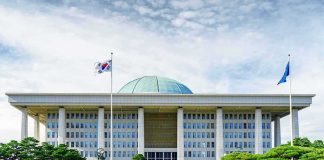 Parliament building with a green dome and flagpoles