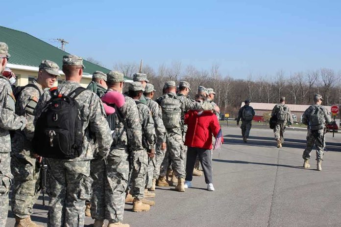 Soldiers in uniform line up outdoors with gear
