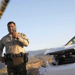 Police officer at crash scene near damaged white car