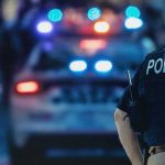 School Bloodshed: Gunman Dead in Minutes police officer in vest near patrol car with flashing lights