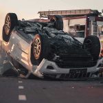 Lawmaker’s Leg Amputated After Vehicle Attack Overturned car on road with firefighters and ambulance