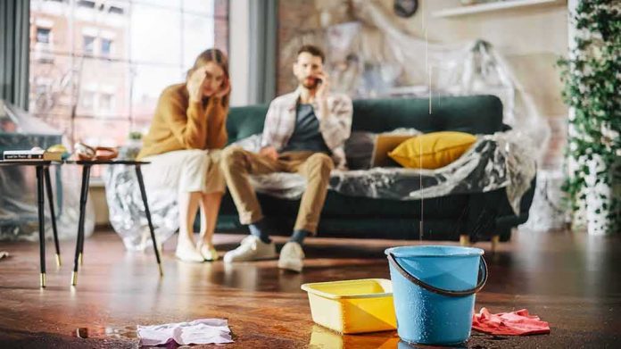 Buckets catching water leak in living room with couple on couch
