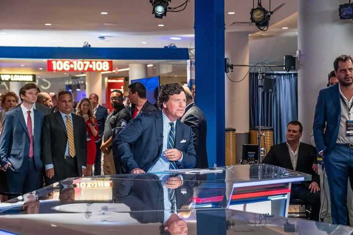 Tucker Carlson at a news desk with Carter Beauford among the onlookers