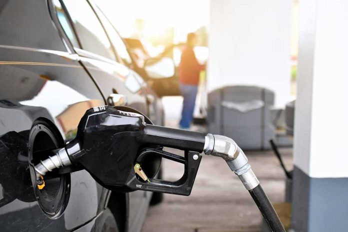 Gas pump nozzle fueling a black car at a station