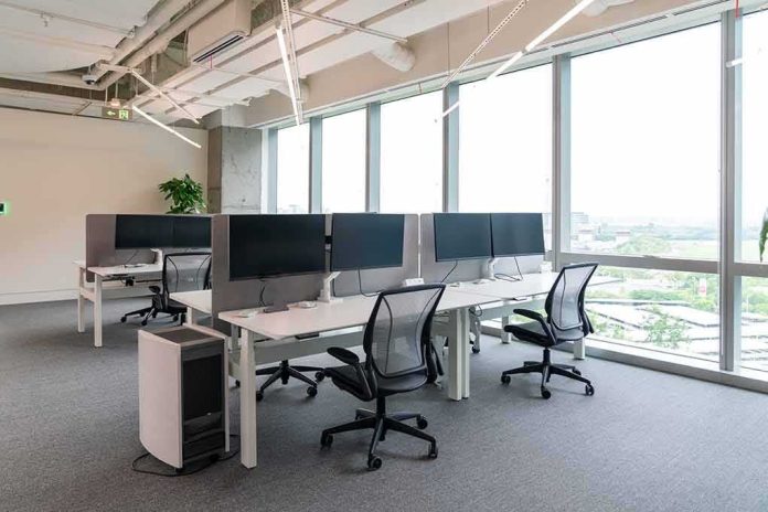 Modern open-plan office with workstations by large windows