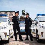Toyota Recalls 31,000 Vehicles Over Crash Risk Jonathan Cyprien with police officers between patrol cars in a city square