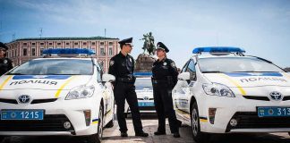 Jonathan Cyprien with police officers between patrol cars in a city square