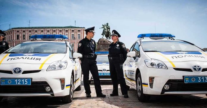 Jonathan Cyprien with police officers between patrol cars in a city square