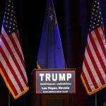 Crowd Erupts As Holyfield Praises Trump Podium with campaign sign between American flags
