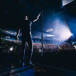 Hecklers Crash – Seinfeld Turns It Into Ammo Singer on stage facing a large concert crowd