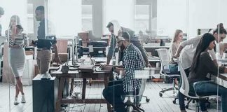 Open-plan office with coworkers collaborating at desks and computers