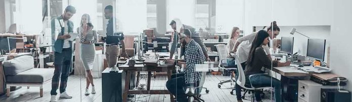 Open-plan office with coworkers collaborating at desks and computers