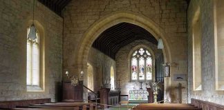 Church interior with wooden pews and stained glass altar